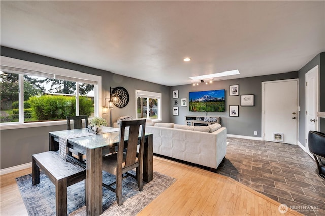 dining space with baseboards, a skylight, and recessed lighting