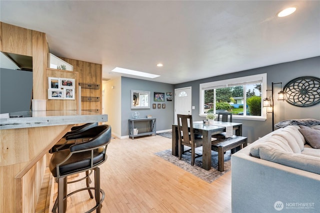 dining room featuring a skylight, light wood-style floors, recessed lighting, and baseboards