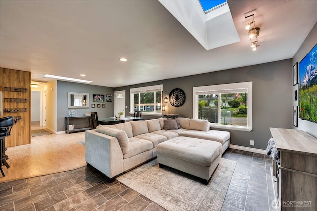 living room with a skylight, recessed lighting, and baseboards