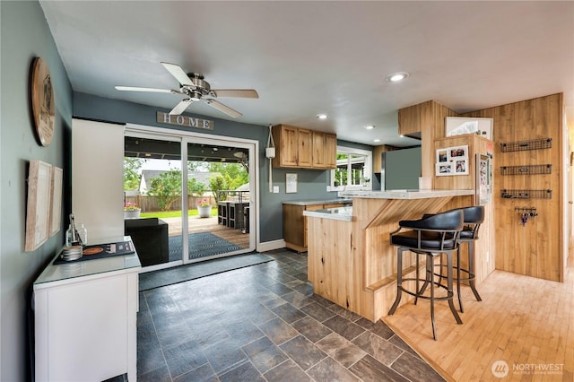 kitchen featuring refrigerator, light countertops, a breakfast bar, a peninsula, and a ceiling fan