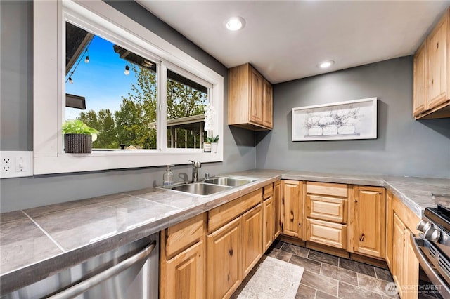 kitchen with appliances with stainless steel finishes, a sink, stone finish flooring, recessed lighting, and tile counters