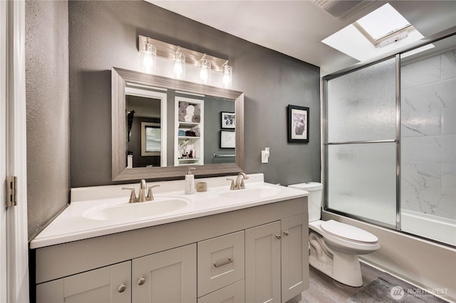 full bath featuring double vanity, toilet, and shower / bath combination with glass door