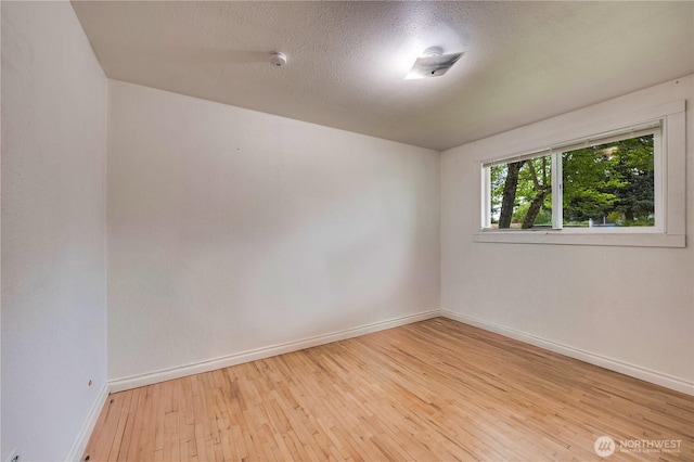 spare room with baseboards, hardwood / wood-style floors, a textured ceiling, and a smoke detector