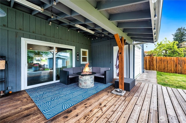 deck with an outdoor living space with a fire pit and fence