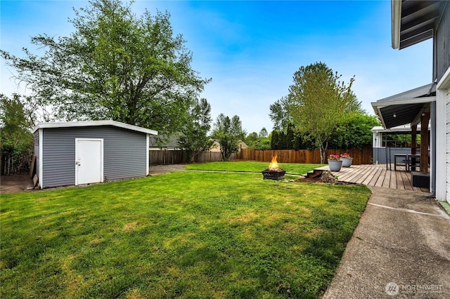 view of yard featuring an outdoor fire pit, a storage unit, a deck, and an outdoor structure