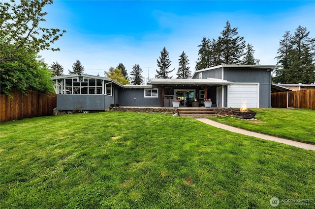 view of front facade with an outdoor fire pit, an attached garage, and a sunroom