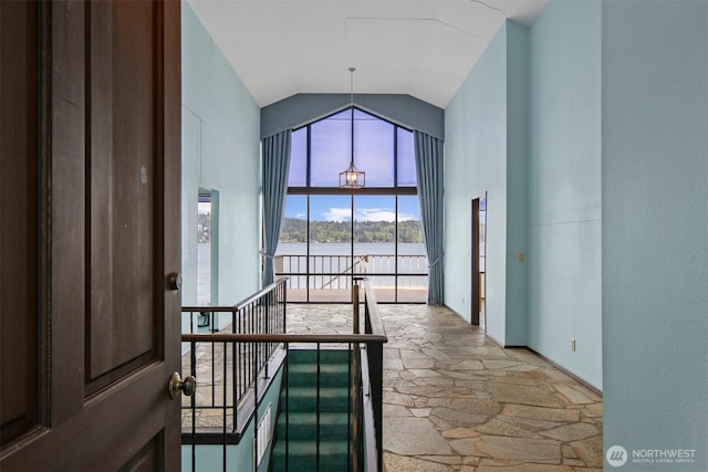 interior space with stone finish floor, a water view, and high vaulted ceiling