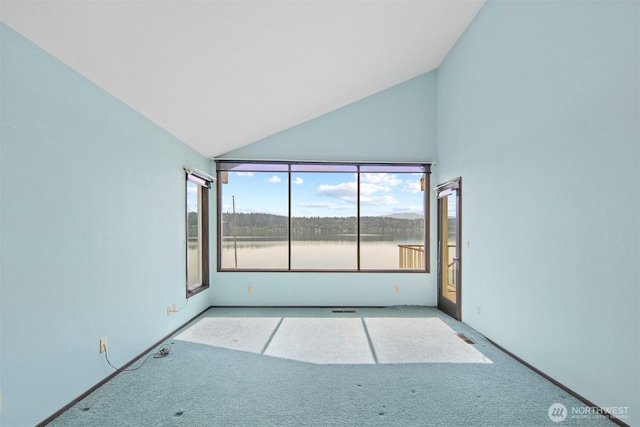 unfurnished room with carpet floors, a water view, and high vaulted ceiling