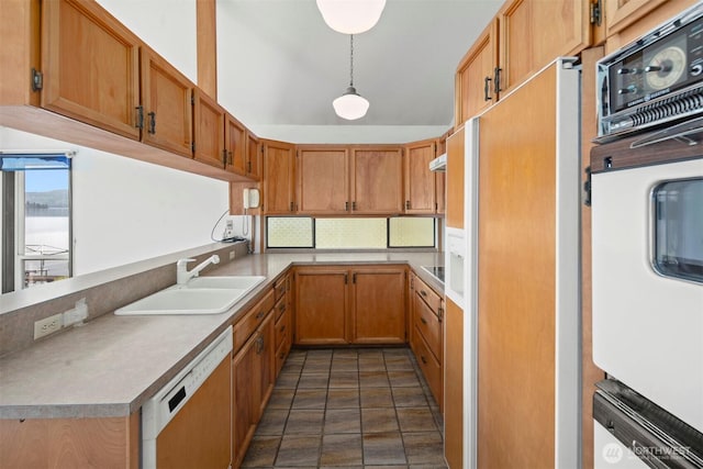 kitchen featuring decorative backsplash, decorative light fixtures, a sink, a peninsula, and dishwashing machine