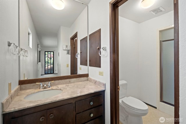 bathroom with vanity, toilet, visible vents, and a stall shower