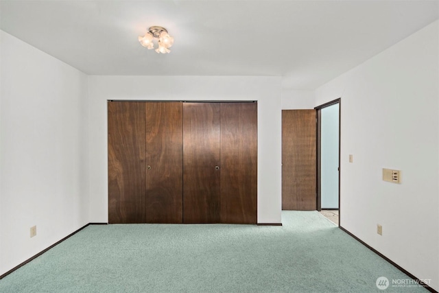 unfurnished bedroom featuring carpet floors, baseboards, and a closet