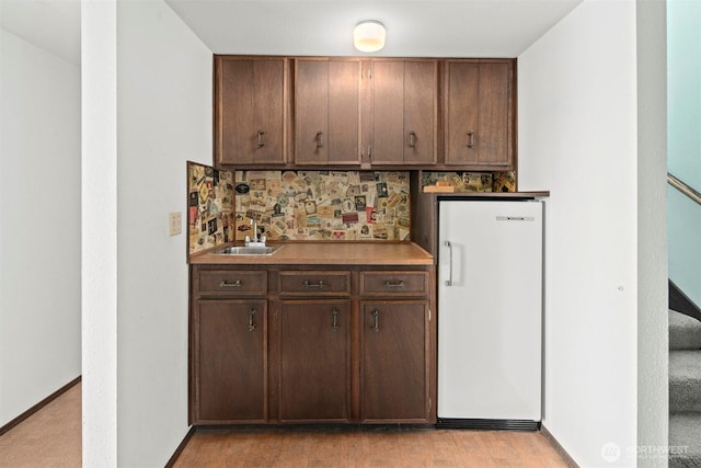 bar featuring tasteful backsplash, a sink, freestanding refrigerator, indoor wet bar, and stairs
