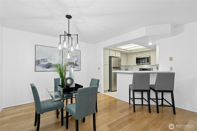 dining space featuring baseboards and light wood-style flooring