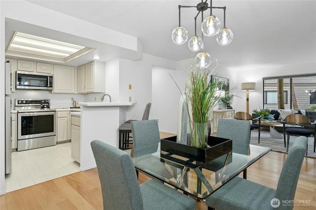 dining area with light wood-style flooring and a tray ceiling