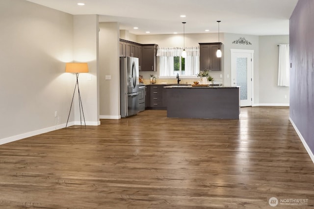 kitchen with dark brown cabinetry, baseboards, dark wood-type flooring, a sink, and stainless steel appliances