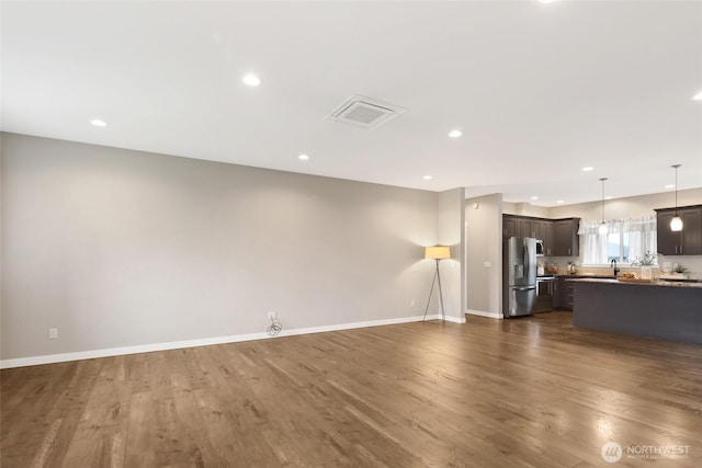 unfurnished living room featuring dark wood-type flooring, recessed lighting, baseboards, and visible vents