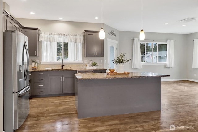 kitchen with plenty of natural light, a sink, light stone counters, and stainless steel appliances