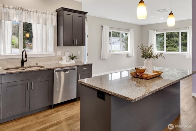 kitchen with light stone countertops, a sink, light wood-style floors, dishwasher, and visible vents
