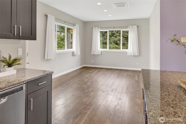 unfurnished dining area with plenty of natural light, baseboards, visible vents, and hardwood / wood-style floors