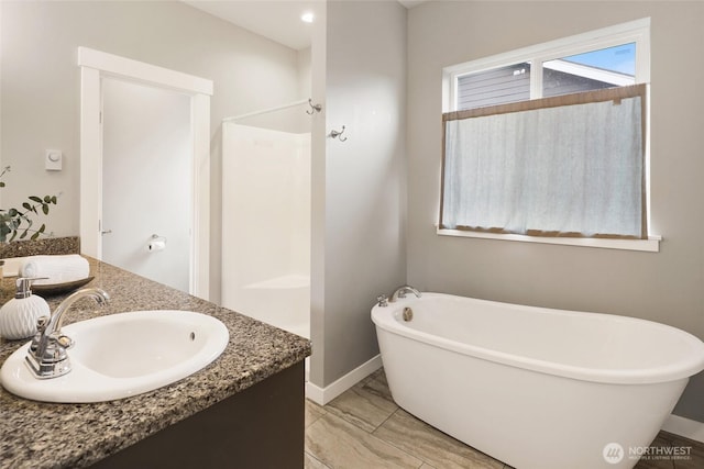 bathroom featuring double vanity, marble finish floor, baseboards, a soaking tub, and a sink