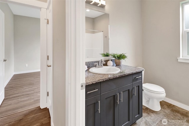 full bath featuring vanity, baseboards, walk in shower, and toilet
