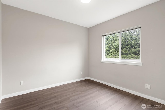 unfurnished room featuring baseboards and dark wood-style floors