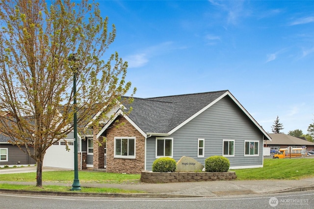 view of front facade with driveway, a front lawn, an attached garage, a shingled roof, and stone siding