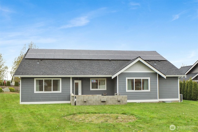 back of property featuring a yard and roof with shingles