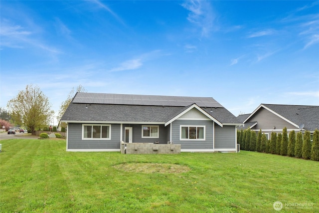 view of front of property with roof mounted solar panels, roof with shingles, and a front yard
