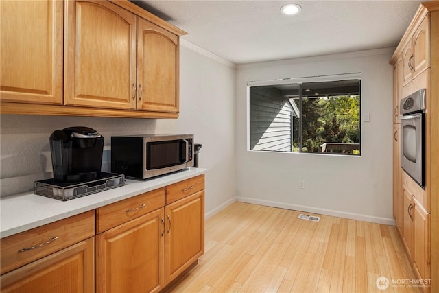 2606 174th Ave NE, Redmond, WA 98052 - kitchen with visible vents, light countertops, light wood finished floors, ornamental molding, and stainless steel appliances