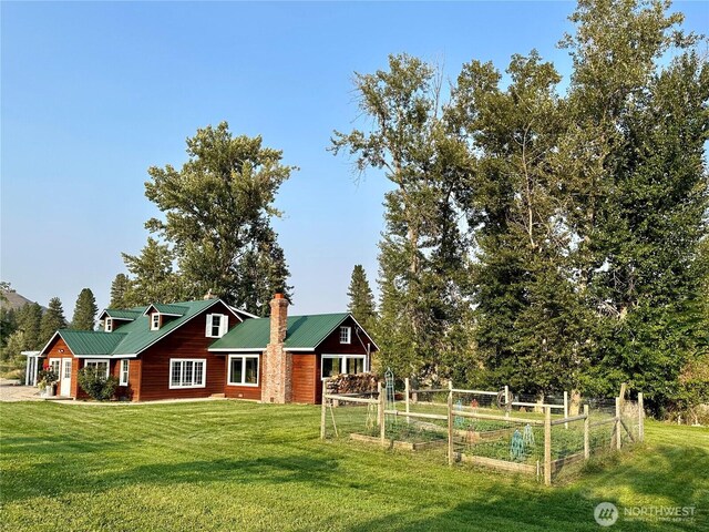 exterior space featuring a chimney, metal roof, a front yard, and a vegetable garden