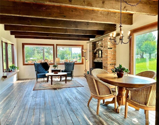 dining space with a fireplace, wood-type flooring, beam ceiling, and a chandelier
