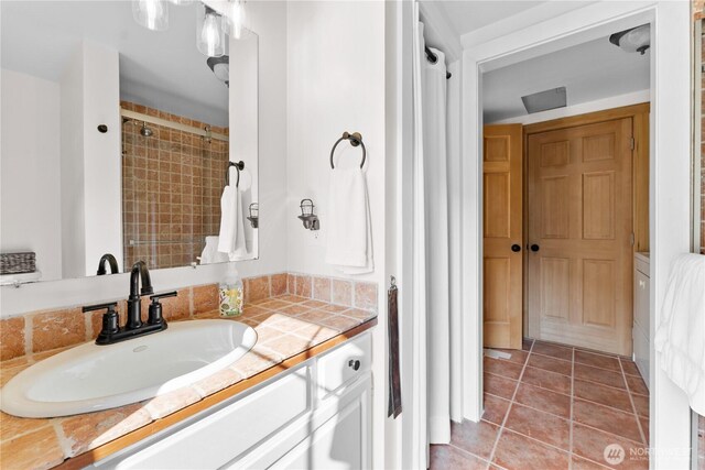 full bathroom featuring vanity, a tile shower, and tile patterned floors