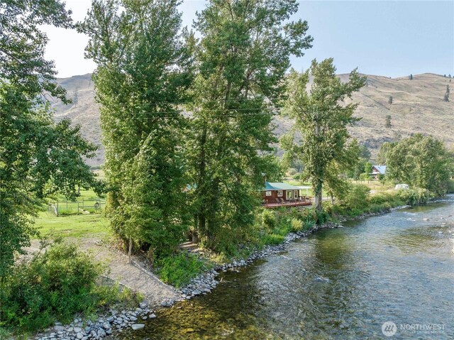 property view of water featuring fence and a mountain view