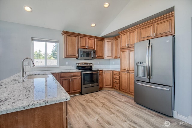 659 Chinook Ave SE, Ocean Shores, WA 98569 - kitchen with appliances with stainless steel finishes, a sink, brown cabinets, light stone countertops, and lofted ceiling