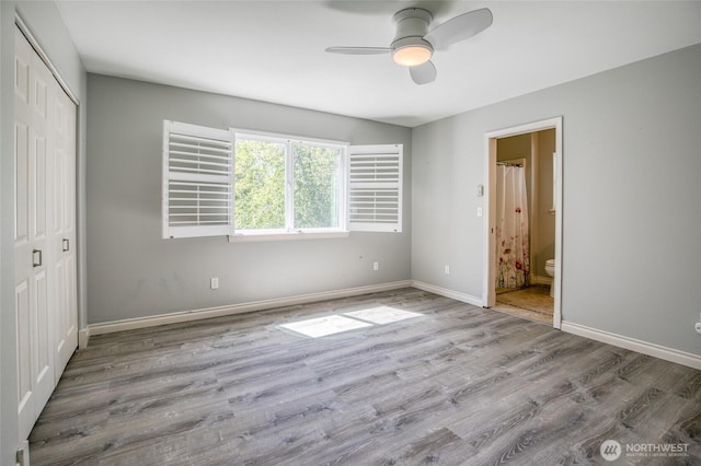 659 Chinook Ave SE, Ocean Shores, WA 98569 - unfurnished bedroom featuring a closet, wood finished floors, baseboards, ensuite bathroom, and a ceiling fan