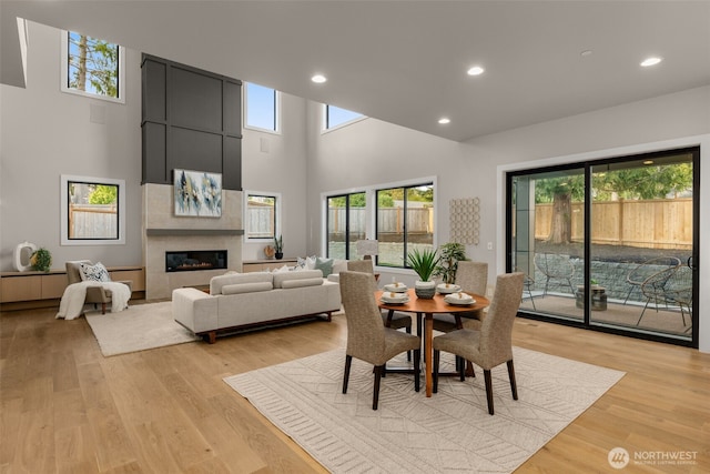 dining room with light wood-type flooring, a healthy amount of sunlight, recessed lighting, and a high ceiling