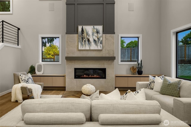 living area with a high ceiling, a glass covered fireplace, and wood finished floors