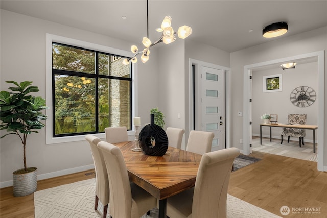 dining room featuring a wealth of natural light, a chandelier, baseboards, and light wood-style flooring