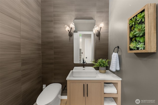 bathroom featuring tile walls, toilet, and vanity