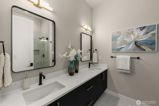 full bath featuring double vanity, baseboards, a stall shower, and a sink