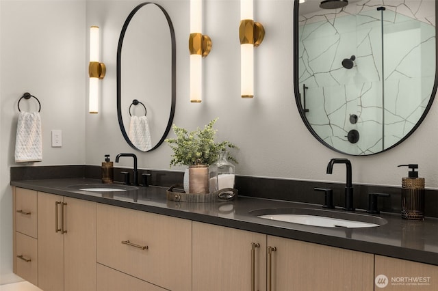 full bath featuring a marble finish shower, double vanity, and a sink