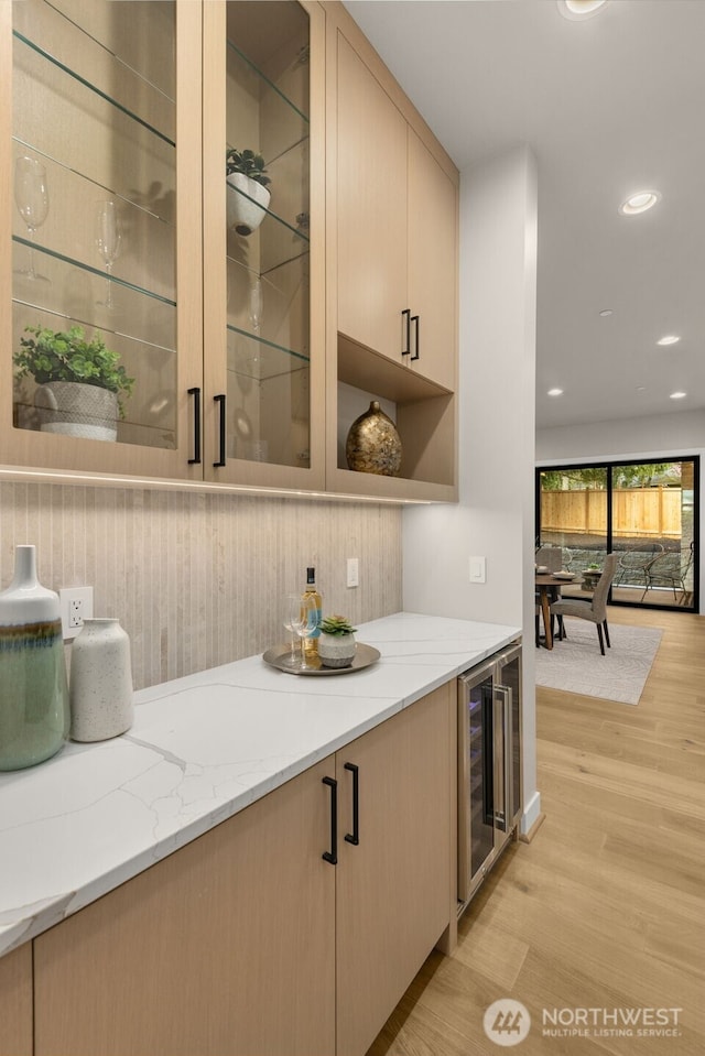 bar featuring light wood finished floors, recessed lighting, and beverage cooler