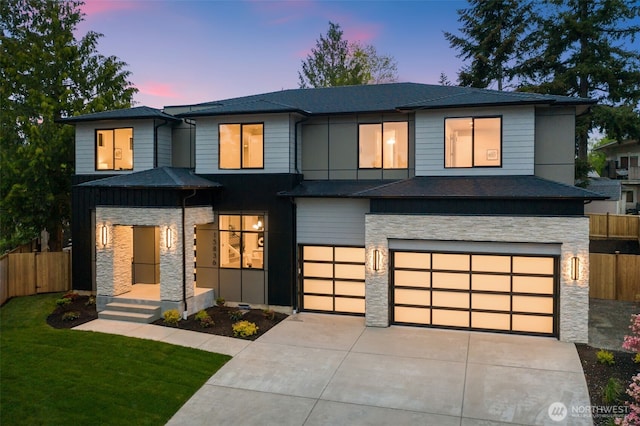 view of front of property featuring fence, an attached garage, stone siding, and driveway