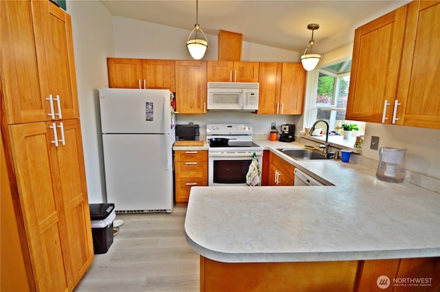 kitchen with lofted ceiling, white appliances, light countertops, a sink, and light wood finished floors