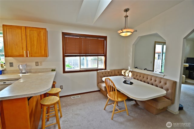 carpeted dining area featuring baseboards, visible vents, and plenty of natural light