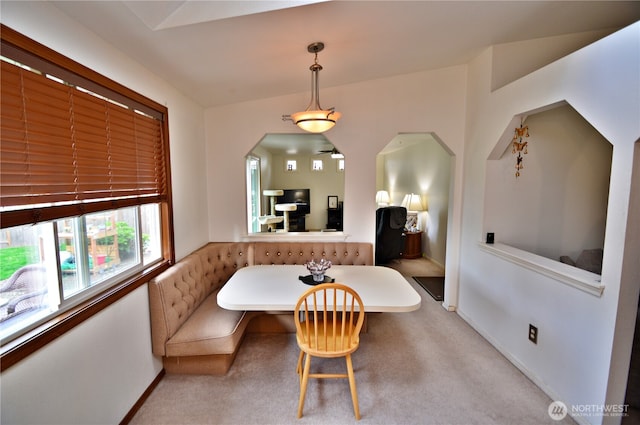 carpeted dining space featuring arched walkways, baseboards, and breakfast area