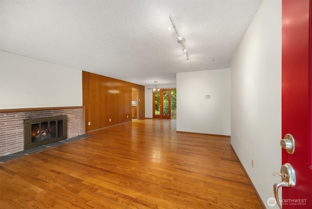 10210 NE 23rd St, Bellevue, WA 98004 - unfurnished living room with a fireplace, a textured ceiling, track lighting, and light wood-type flooring