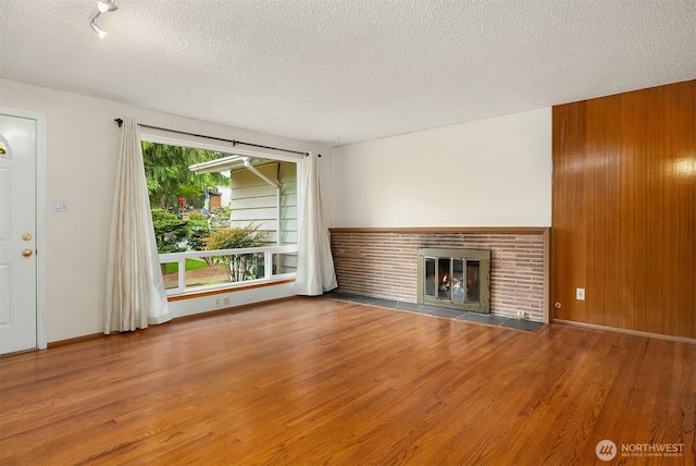 10210 NE 23rd St, Bellevue, WA 98004 - unfurnished living room with a textured ceiling, a brick fireplace, wood finished floors, and wooden walls