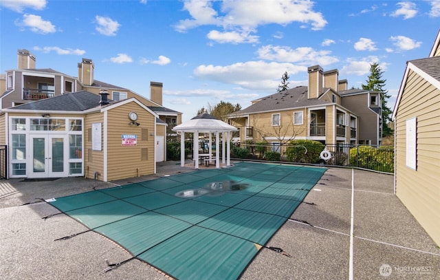 pool with fence, a gazebo, an outbuilding, a patio area, and french doors